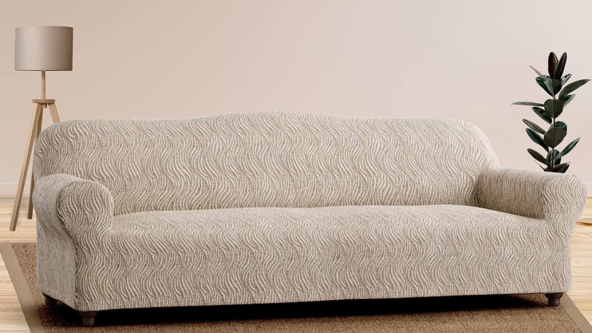 A beige PAULATO BY GA.I.CO. Stretch Sofa Slipcover with a textured wave pattern covers a classic sofa in a modern living room with neutral decor.