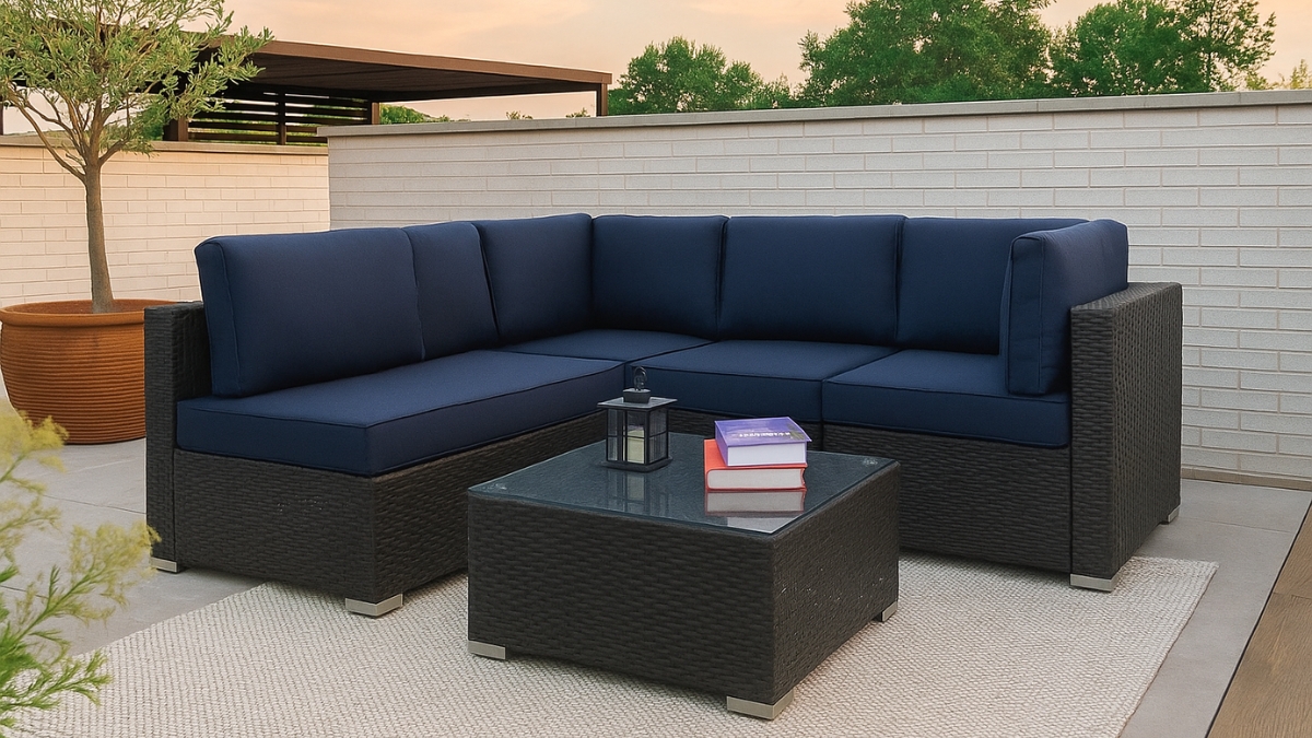A wicker patio furniture set with navy blue cushions and a glass-top table on a rooftop deck.
