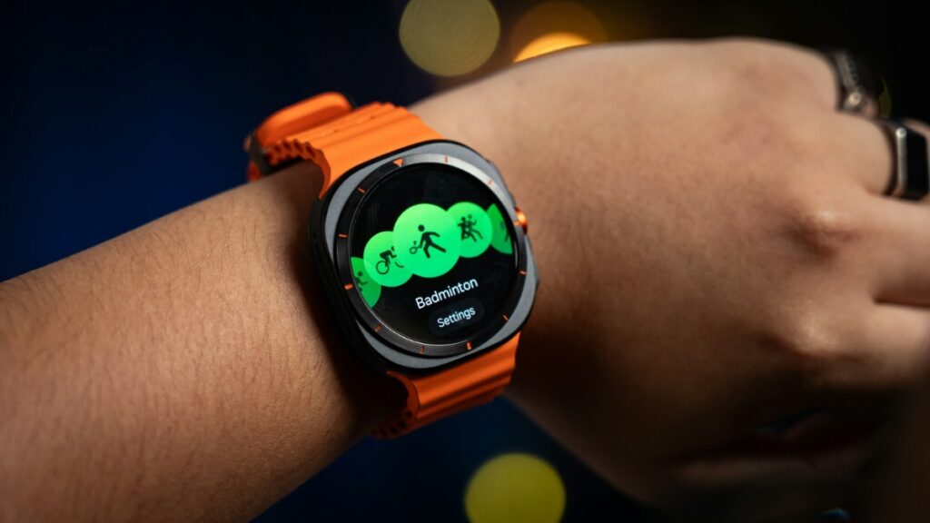 Samsung Galaxy Watch Ultra with an orange band showing the badminton workout screen on the fitness tracking menu.