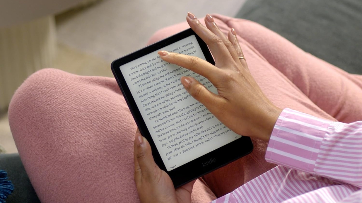 A person reads on an Amazon Kindle Paperwhite Signature Edition while relaxing in cozy clothes.