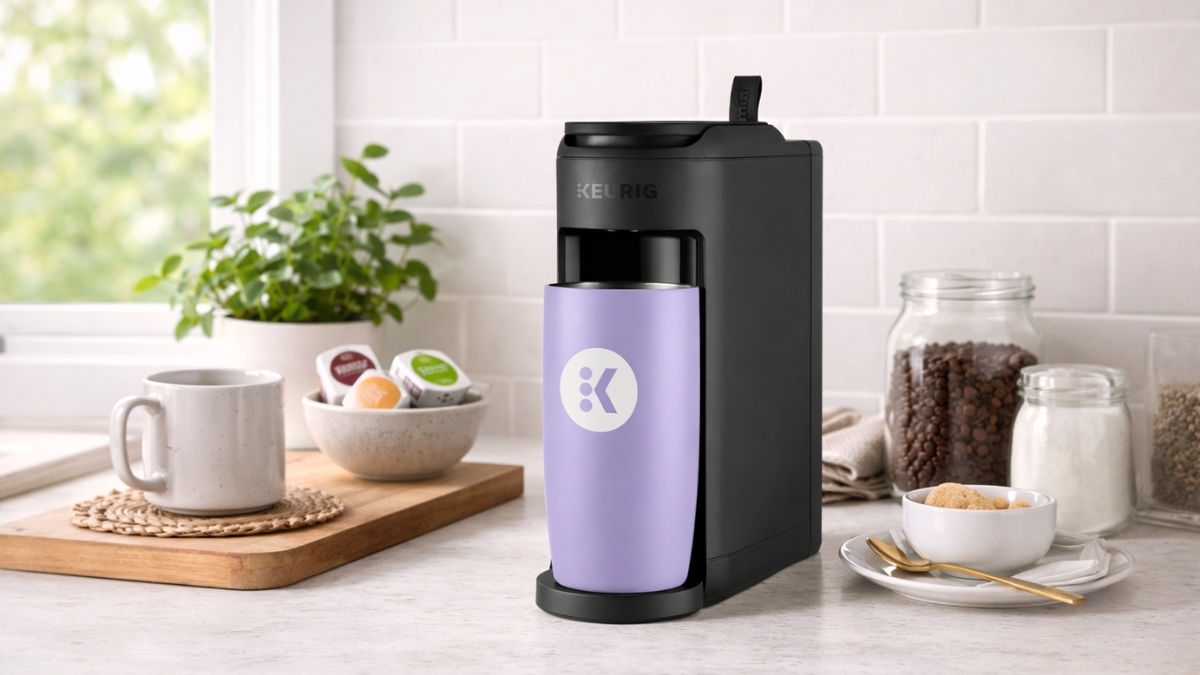 Keurig K-Mini Mate Single Serve Coffee Maker brewing coffee on a kitchen counter with a travel mug, K-Cup pods, and compact space-saving design