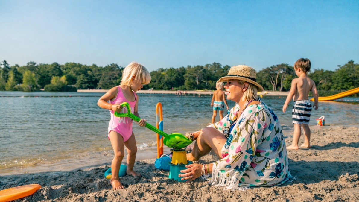 Family enjoying EuroParcs Holiday By The Water beach with children playing by lake