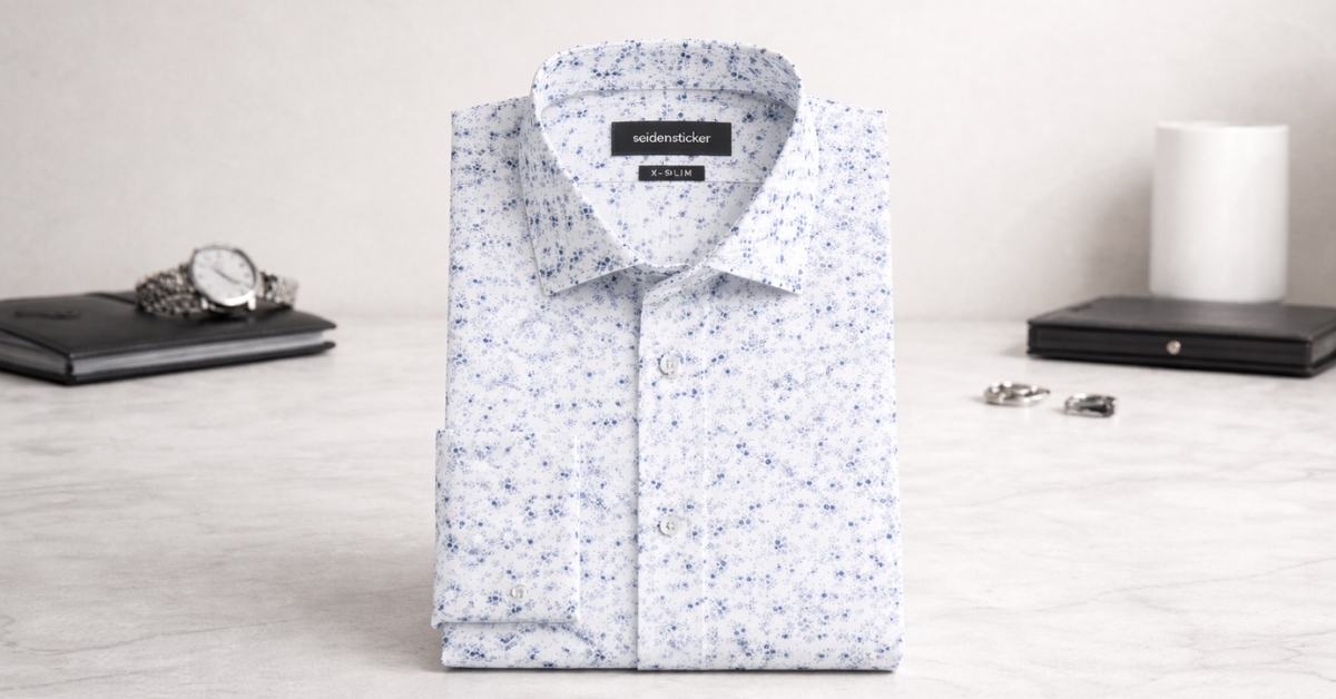 Seidensticker X-Slim Business Hemd Druck with light blue printed pattern, folded dress shirt on modern desk background