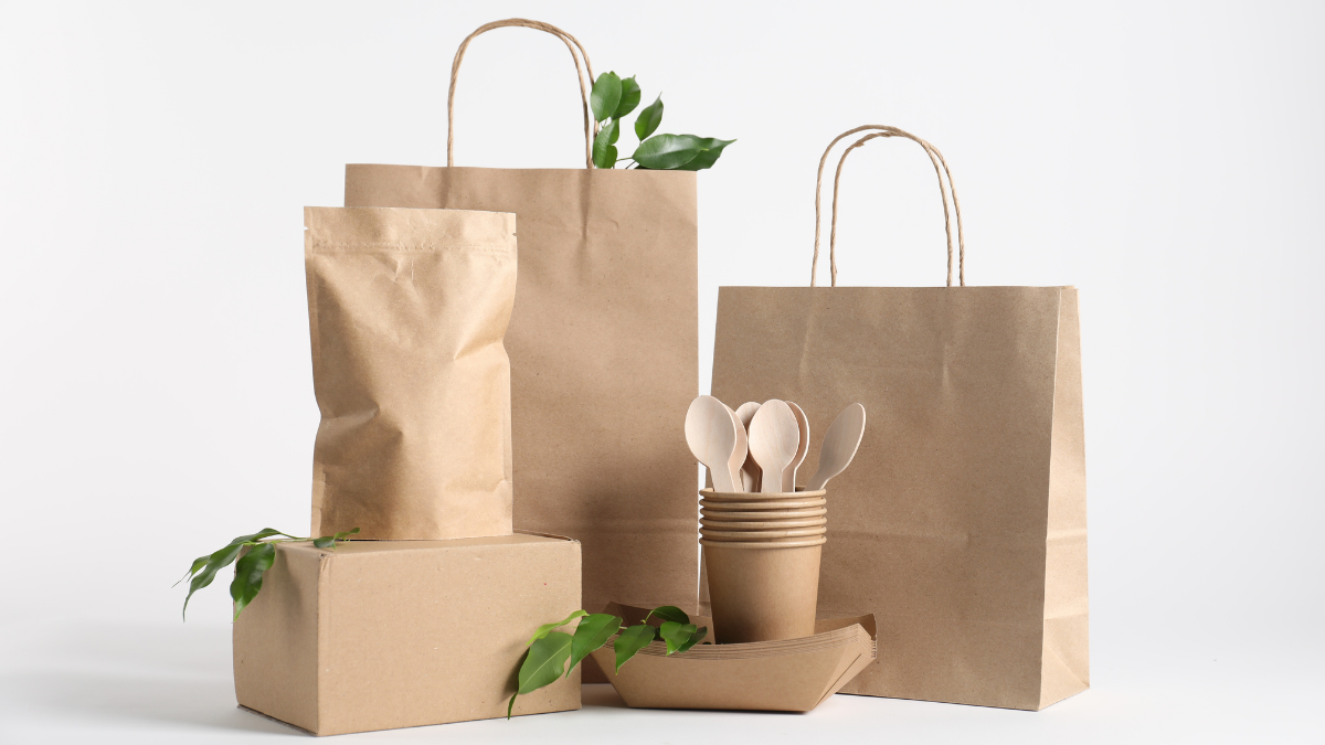 Eco-friendly packaging including kraft paper bags, cardboard boxes, wooden utensils, and biodegradable food containers.